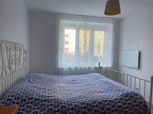 a bedroom with a bed with a blue comforter and a window at Stadtwohnung Villach Lind in Villach