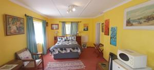 1 dormitorio con cama y pared amarilla en Millgate Cottage, en Balgowan