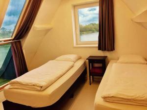 een kleine kamer met 2 bedden en een raam bij vakantiewoning het vijverhuis in Zillebeke