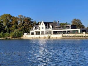 een groot wit huis aan de oever van een meer bij vakantiewoning het vijverhuis in Zillebeke