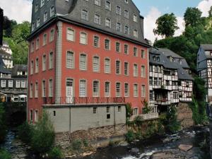 ein großes rotes Backsteingebäude neben einem Fluss in der Unterkunft Linden 4 in Monschau