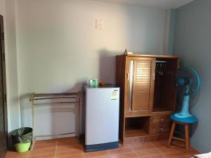 a kitchen with a refrigerator and a wooden cabinet at Chandra Hostel Koh Tao in Koh Tao