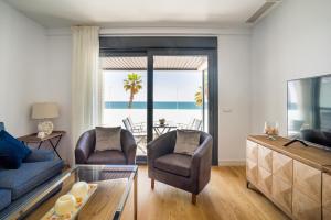 ein Wohnzimmer mit einem Sofa, Stühlen und einem TV in der Unterkunft Gran vivienda de lujo frente al mar in Málaga