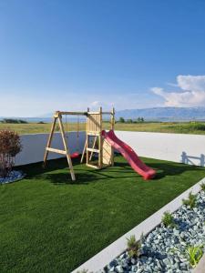 a playground with a slide on the grass at Villa Royal Sands in Privlaka