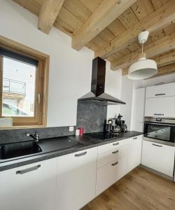a kitchen with white cabinets and a sink and a window at Chalet Le Clapière in La Toussuire