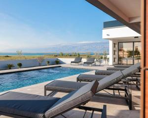 a row of lounge chairs next to a swimming pool at Villa Royal Sands in Privlaka