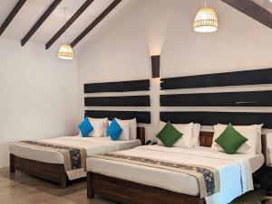 - 2 lits dans une chambre avec des oreillers bleus et verts dans l'établissement Pinthaliya Resort, à Sigirîya