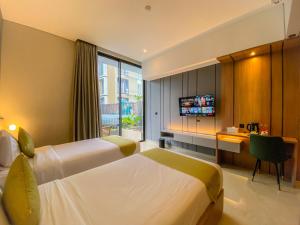 a hotel room with two beds and a desk and a television at Facade Hotel by Azana in Tawangmangu