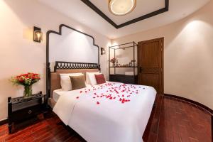 een slaapkamer met een wit bed met rode bloemen erop bij Secret Garden Hotel in Ho Chi Minh-stad