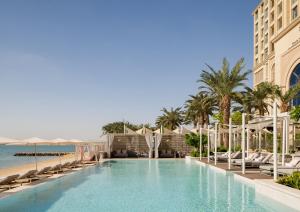 uma piscina ao lado de uma praia com palmeiras em Four Seasons Resort and Residences at The Pearl - Qatar em Doha