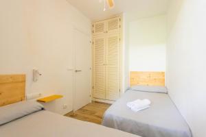 2 Betten in einem Zimmer mit weißen Wänden und Holzböden in der Unterkunft Son Bou Gardens Deluxe 2 in Son Bou