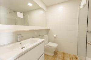 a white bathroom with a sink and a toilet at Son Bou Gardens Deluxe 2 in Son Bou