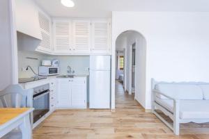 a kitchen with white cabinets and a table and a chair at Son Bou Gardens Deluxe 2 in Son Bou