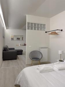 una camera bianca con un letto e una sedia di 7Suites a Empoli