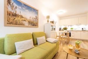 a living room with a green couch and a kitchen at Haus Strandburg - hinter Düne und Meer in Binz