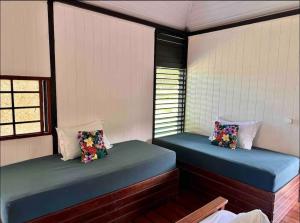 two beds in a room with two windows at Fare miti access private white sand beach in Moorea