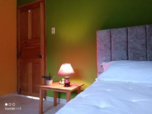 um quarto com uma cama e uma mesa com um candeeiro em Buenavista, espacio natural em Ráquira