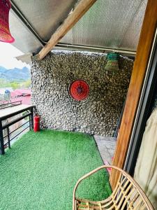 a red clock on a stone wall with a chair at Du Gia Village Homestay-Lana in Làng Cac