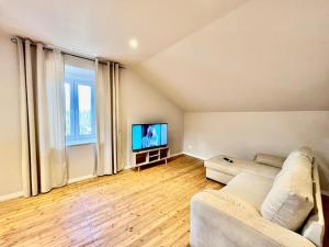 a living room with a couch and a flat screen tv at LesCinqSuites/12 couchages-DABNB in Limoges