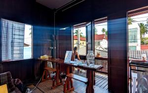 a person sitting at a table with a laptop on a balcony at Aforetime House @ Samui in Taling Ngam Beach