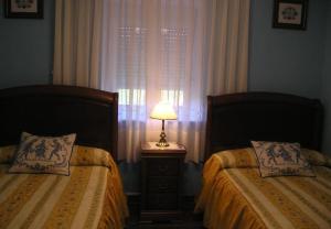 um quarto com 2 camas e um candeeiro numa mesa de cabeceira em Finca El Carbayal em El Campo