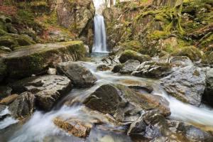 a waterfall in the middle of a river with rocks at Tarn Hut in Rydal