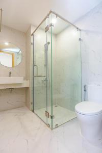 La salle de bains est pourvue d'une douche en verre et de toilettes. dans l'établissement TMS Beachfront Apartment Quy Nhon Bay, à Quy Nhơn