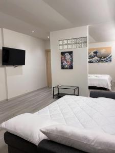 1 dormitorio con 1 cama blanca y TV de pantalla plana en 7Suites, en Empoli