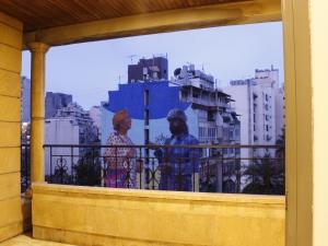 2 Personen stehen auf einem Balkon mit Blick auf Gebäude in der Unterkunft Viccini Suites in Beirut