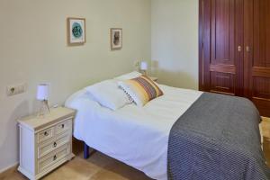 1 dormitorio con cama blanca y mesita de noche en A villiña de areas, en Sanxenxo