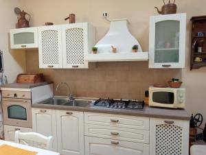 a kitchen with white cabinets and a sink and a microwave at Casa di Dario in Pettenasco