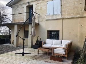 een patio met een bank, een tafel en een parasol bij Les rives de Port Neuf in Saint-André-de-Cubzac