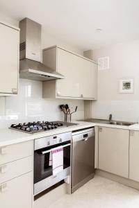 a kitchen with white cabinets and a stove top oven at Madison Hill - Fernlea View 4 - Two bedroom flat in London