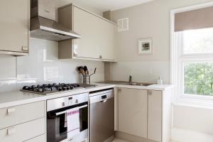 ロンドンにあるMadison Hill - Fernlea View 4 - Two bedroom flatのキッチン(白いキャビネット、コンロ付)