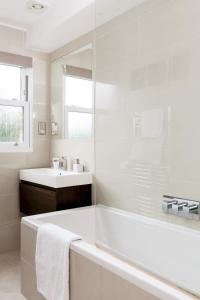 a white bathroom with a tub and a sink at Madison Hill - Fernlea View 4 - Two bedroom flat in London