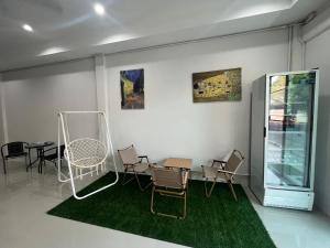 a room with chairs and a table and a green rug at BeHome and Hostel in Chiang Mai