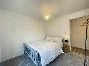 um quarto com uma cama com lençóis brancos e um candeeiro em New Luxury Modern Apartment em Milton Keynes