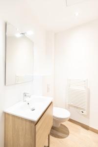 a white bathroom with a sink and a toilet at Eldorado - Résidence Hestia in Saint-Étienne