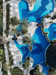 an aerial view of a resort swimming pool with palm trees at Prinsotel La Dorada & Spa in Playa de Muro