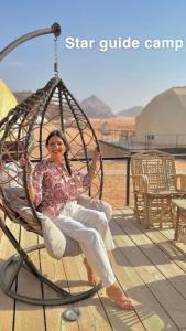 Uma mulher está sentada num baloiço. em Star Guide Camp em Wadi Rum
