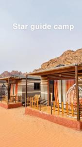 une maison dans le désert avec des tables et des chaises dans l'établissement Star Guide Camp, à Wadi Rum