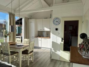 a kitchen and dining room with a table and a clock at Boerenslag 41 in Sint Maartensvlotbrug