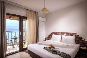 um quarto de hotel com uma cama e uma varanda em Sunlight Elounda - Adults only Hotel "by Checkin" em Agios Nikolaos
