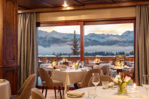 a restaurant with tables and chairs and a large window at Guarda Golf Hotel & Residences in Crans-Montana