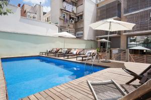 a swimming pool with chairs and an umbrella on a building at Barcino Inversions - Bright Apartment in Gracia with shared Pool in Barcelona