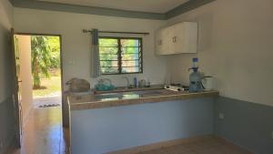 cocina con fregadero y ventana en Tradewins Cottage, en Diani Beach