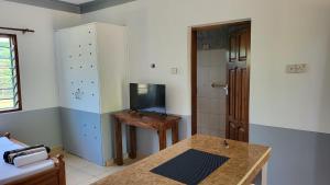 Habitación con mesa, TV y baño. en Tradewins Cottage, en Diani Beach