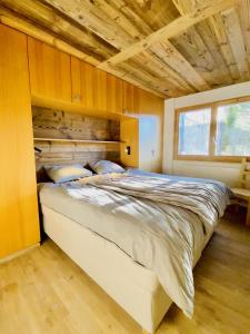 Fontanettaz V 007 - MOUNTAIN & VIEW apartment 8 pers في فييسوناز: غرفة نوم بسرير كبير بسقف خشبي