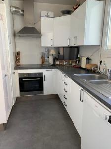 una cocina con armarios blancos y fregadero en L'ELEGANCE SOUS LE SOLEIL, en Levallois-Perret