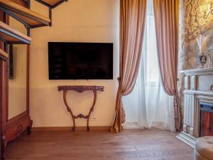 a living room with a tv and a table and curtains at Suite Contessa Isabella in Bracciano +10 photos
